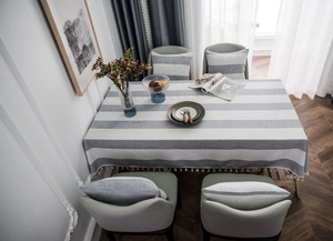 Detail of grey and white striped linen tablecloth featuring elegant fringe tassels on the edge