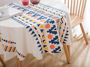 Détail d'une nappe ronde en lin aux motifs géométriques bohèmes drapée sur une table blanche