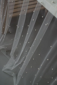 Macro detail of white tulle fabric with elegant pearl beads for dessert table decor