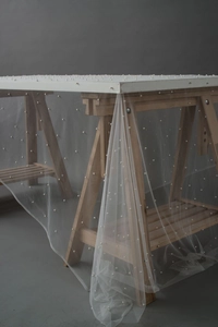 Close-up of white sheer tulle fabric with elegant pearl beads for cake table decoration