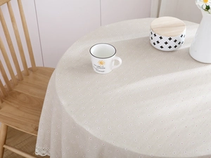 Close-up of beige cotton linen round tablecloth with daisy print and lace trim