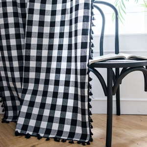Black and white gingham cotton linen curtain with tassel trim in a cozy home setting