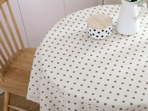 Close-up of daisy pattern on cotton linen tablecloth with white lace floral edges