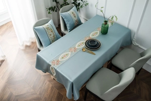 Detail of light blue rectangle tablecloth and matching cushions with floral embroidery