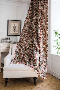 Detail of bohemian geometric pattern curtain with colorful pom-pom edge on a chair