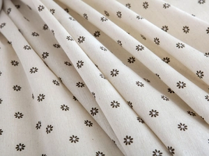 Detail of cotton linen fabric featuring small brown floral prints on cream base