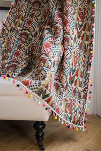 Detail of colorful bohemian jacquard curtain with geometric patterns and pom-pom trim