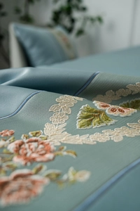 Close-up of elegant floral embroidery on premium grey-blue silk texture fabric