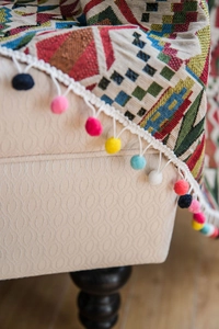 Detail showing Bohemian geometric curtains with colorful pom-pom fringe and woven texture