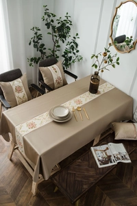 Close-up of elegant beige floral embroidery on tablecloth with matching table runner