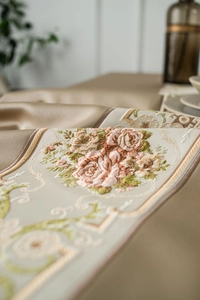 Close-up of champagne satin table runner with elegant rose embroidery and gold border