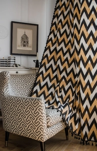 Detail of bohemian curtain with black tassels and golden zigzag wave patterns