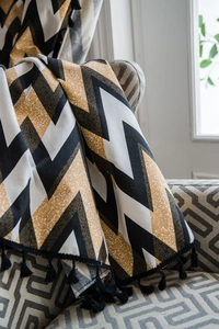 Close-up of geometric wave pattern fabric with decorative black fringe tassels