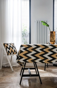 Detail of bohemian gold wavy chevron tablecloth and matching pillow on a dining table