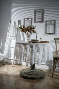 Close-up of white lace tablecloth with floral hollow patterns and scalloped edges