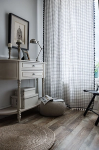 Close-up of Nordic style black and white checkered curtain with elegant black pom-pom fringe