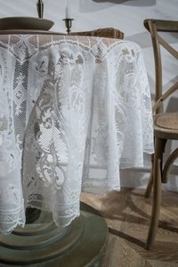 Close-up of elegant white lace tablecloth with floral patterns and scalloped edges