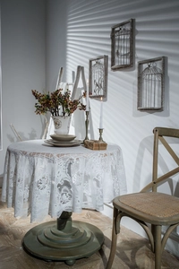 Detailed close-up of intricate floral lace patterns and scalloped edges on a round tablecloth