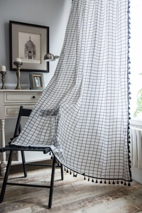 Detail showing white grid curtains with black fringe tassels on a wooden chair