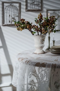 Close-up of white round lace tablecloth with floral hollow embroidery and elegant vintage texture