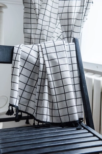 Close-up of white grid curtain with black check pattern and handmade tassel fringe detail