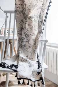 Detail of floral printed cotton linen curtain with decorative black fringe tassel edge