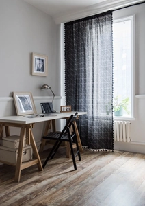 Détail d'un rideau noir géométrique moderne avec motifs en maille blanche et pompons