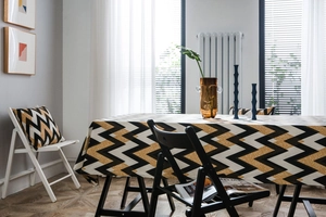 Detail of bohemian gold wavy tablecloth and matching pillow cover in a modern dining room