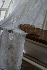 Close-up of elegant white floral lace tablecloth with intricate embroidery on vintage wood