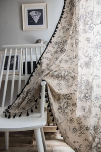 Detail of rose floral print cotton linen curtain with black tassel fringe trim