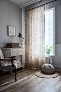 Close-up of vintage script printing and black tassel fringe on cream cotton linen curtain