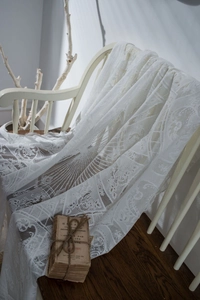 Close-up of white lace tablecloth showing intricate floral embroidery and wavy edges