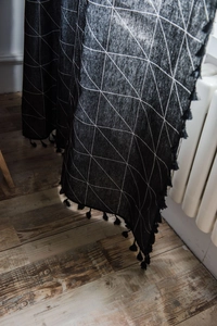 Détail de rideau en coton et lin à imprimé géométrique noir avec bordure à pompons fins