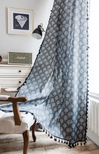 Detailed view of tree print linen curtain with black tassel fringe and soft fabric texture