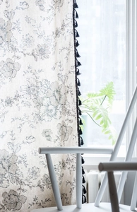 Close-up of vintage floral cotton linen curtain with black tassel fringe detail