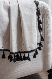 Detail der Vorhang mit Gänseblümchen-Print und schwarzen Fransen auf einem weißen Sofa