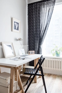Détail d'un rideau noir à motif géométrique avec franges à pompons en coton et lin