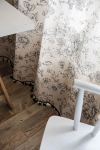 Detail of vintage floral pattern and black tassel trim on cotton linen kitchen curtain