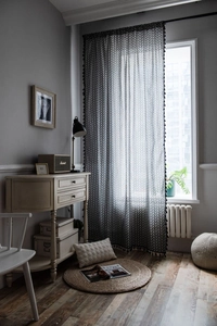 Detail of grey geometric herringbone curtain with black tassel fringe and semi-sheer fabric
