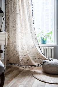 Close-up of vintage cotton linen curtain with black letter print and tassel fringe