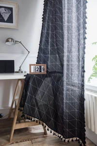 Détail de tissu géométrique noir en coton et lin avec glands dans un bureau moderne