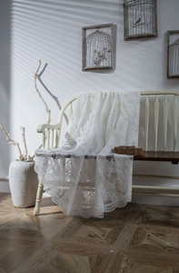 Detailed view of white floral lace tablecloth with elegant scalloped edges in sunlight