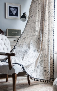 Close-up of vintage script prints and black tassel fringe on cotton linen small curtain