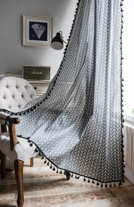 Detail of grey geometric chevron pattern curtain with black tassel fringe on sofa