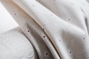 Detailaufnahme von Gänseblümchenmuster auf beige Baumwollleinenstoff mit rotem Blumendruck