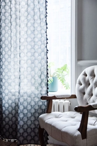 Detailed view of dark blue curtain fabric with white tree print and black pom-pom trim