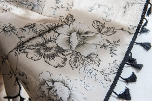 Detailed close-up of cotton linen floral curtain with elegant black tassel trim details
