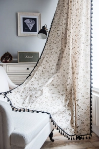 Detail of floral linen curtain featuring navy blue tassels and a semi-sheer texture