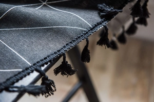 Détail d'un imprimé géométrique noir moderne sur rideau en lin avec des franges noires