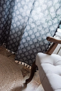 Detailed close-up of tree print fabric texture with black fringe tassels on the curtain edge